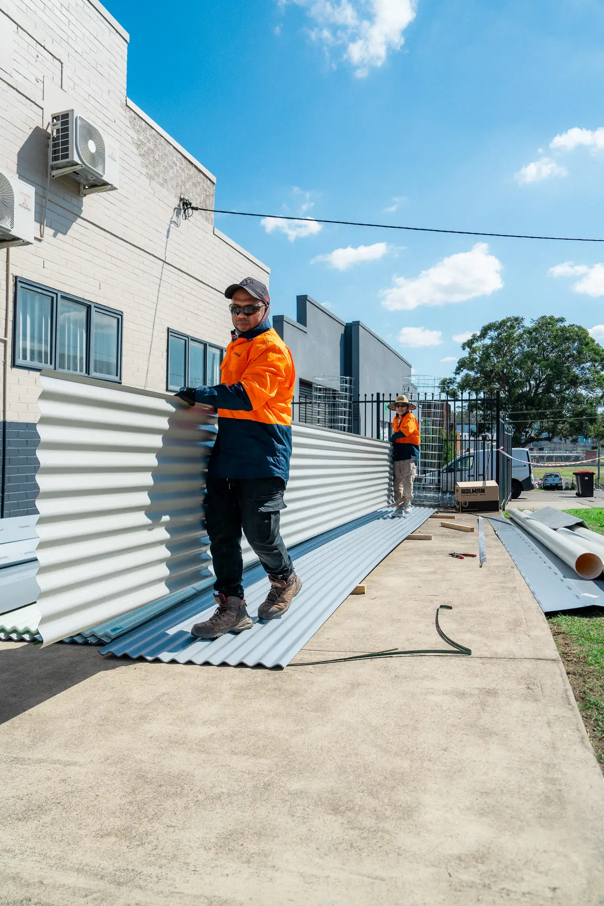 Roofer handling new corrugated sheets beside a factory wall