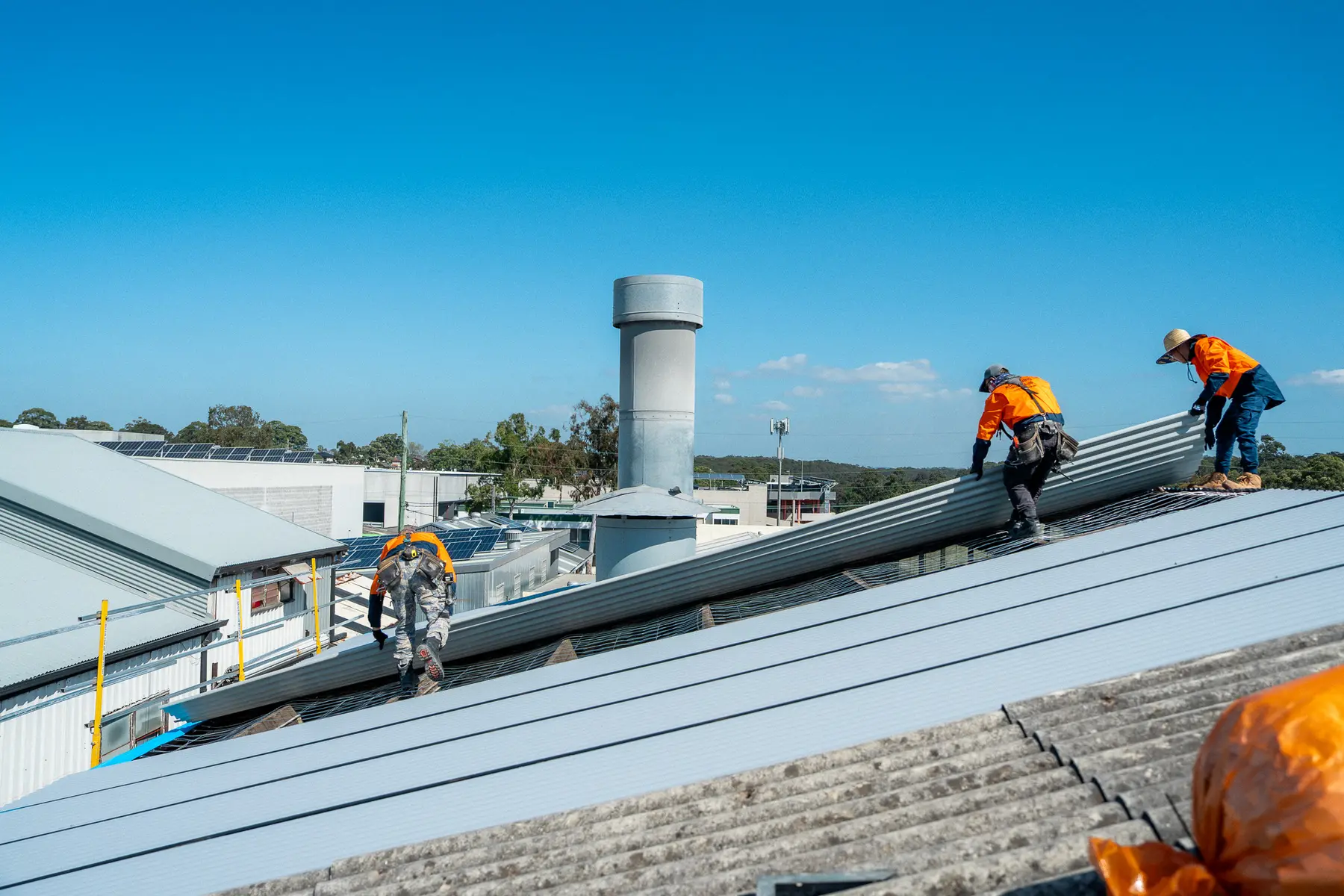 AD Roofing crew laying new sheets on a large industrial roof