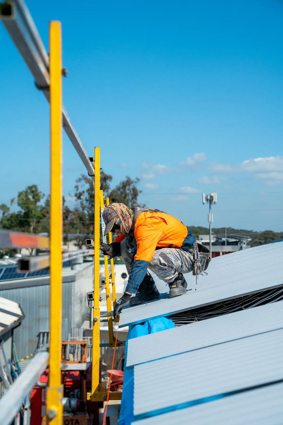 Roofer working at the roof edge behind yellow edge-protection rails