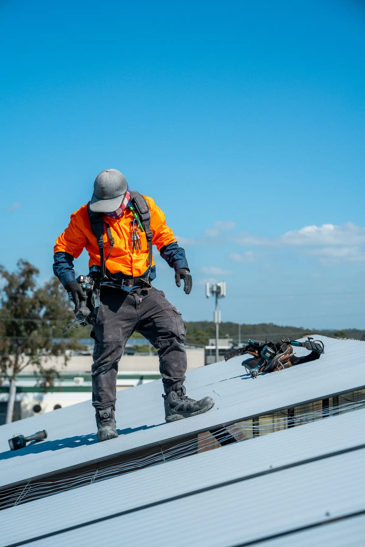 AD Roofing roofer in a safety harness walking across a newly laid metal roof