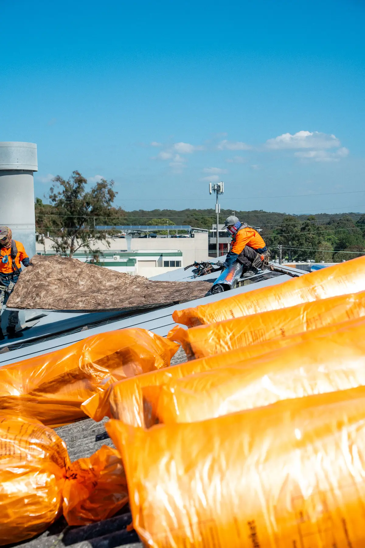 Wrapped roofing materials staged on the roof beside the work area