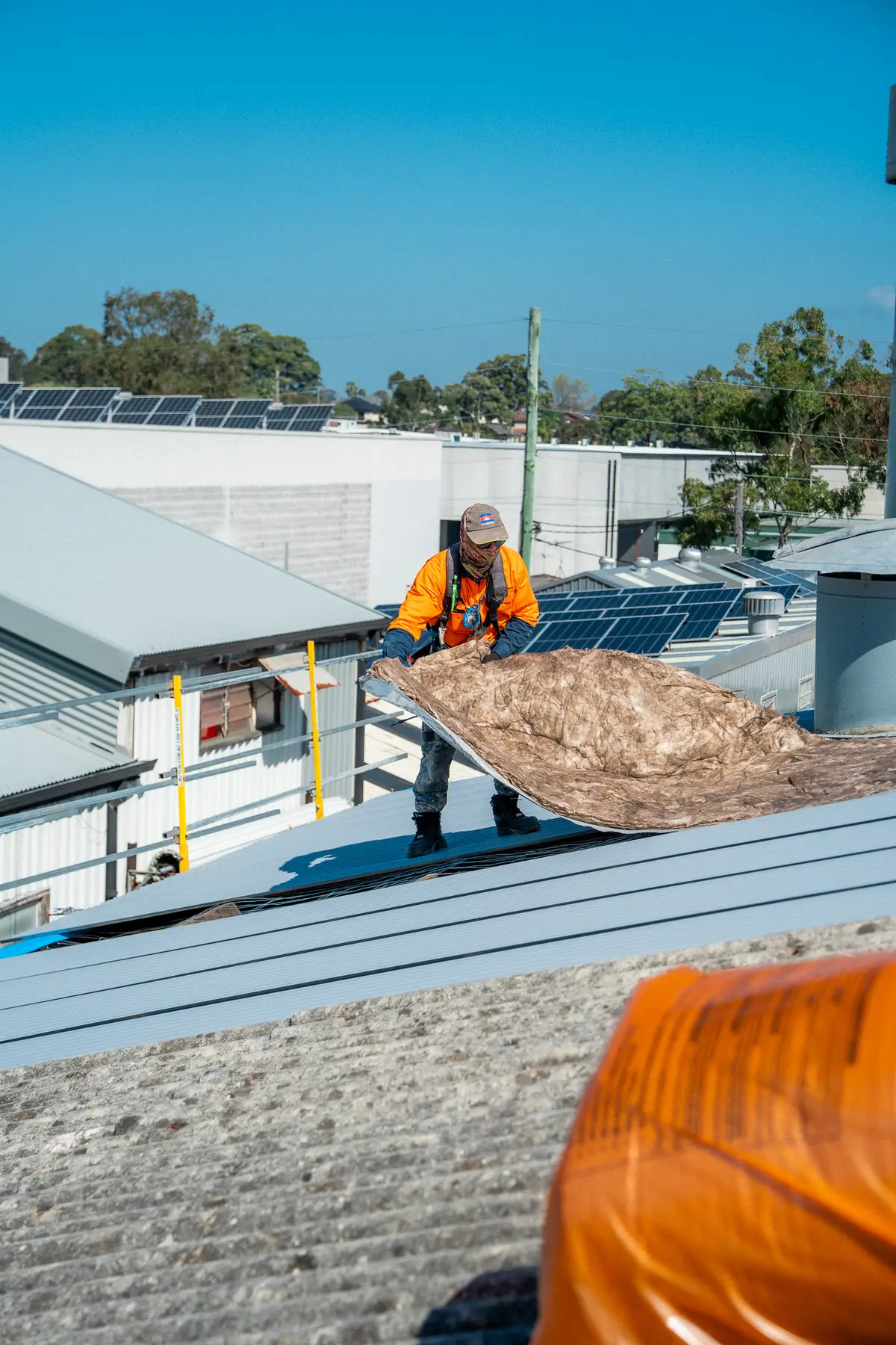 Roofer lifting old insulation blanket off the roof structure