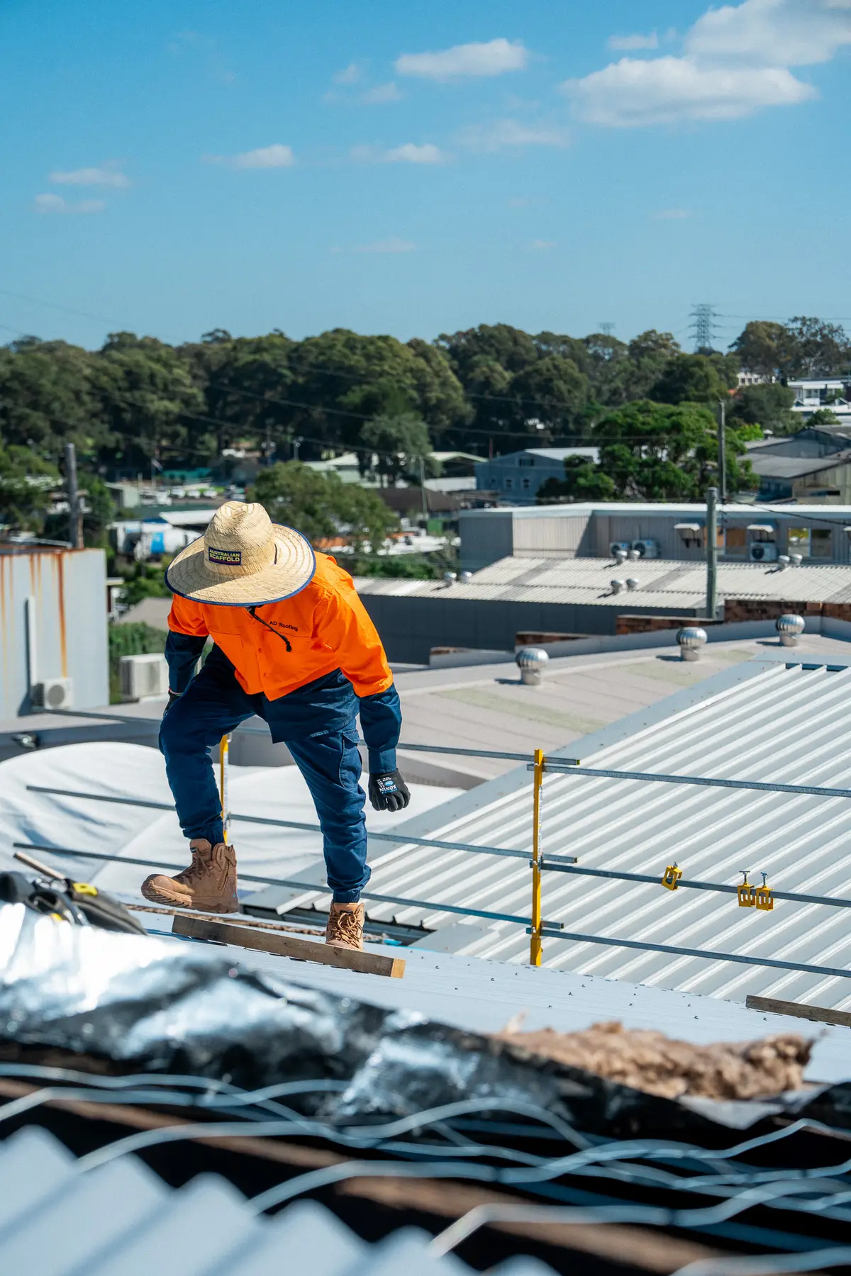 Roofer working over the roof purlins with safety mesh and foil insulation