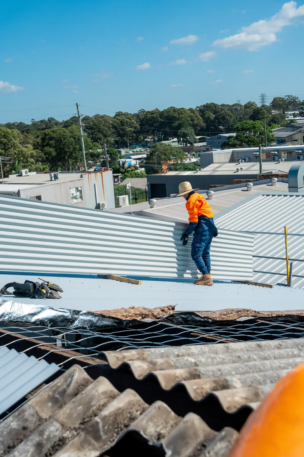Roofer setting a new sheet in place beside old corrugated sheeting