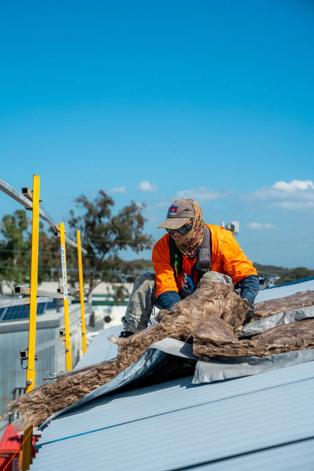 Roofer pulling up old insulation blanket near the edge-protection rail