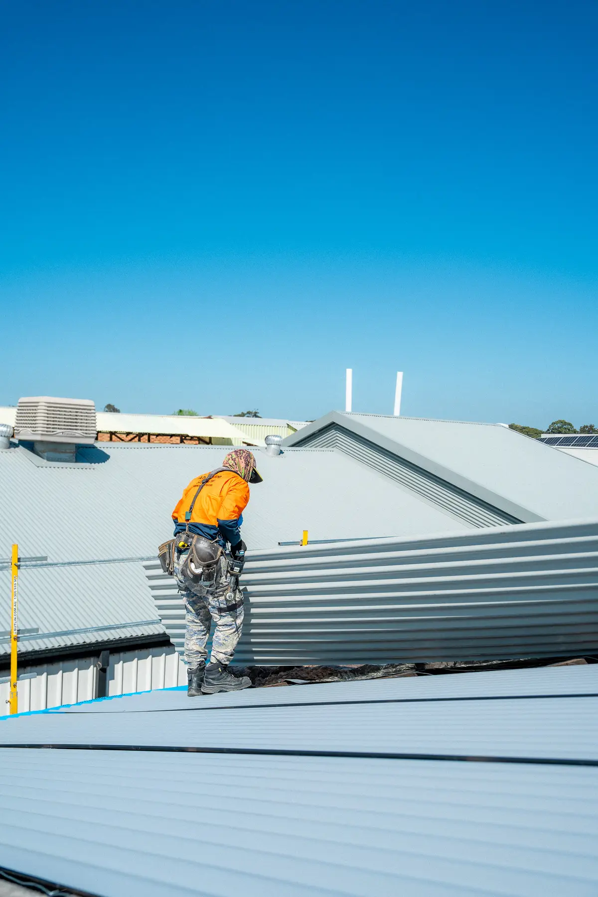 Roofer lifting the edge of a new sheet while laying the metal roof