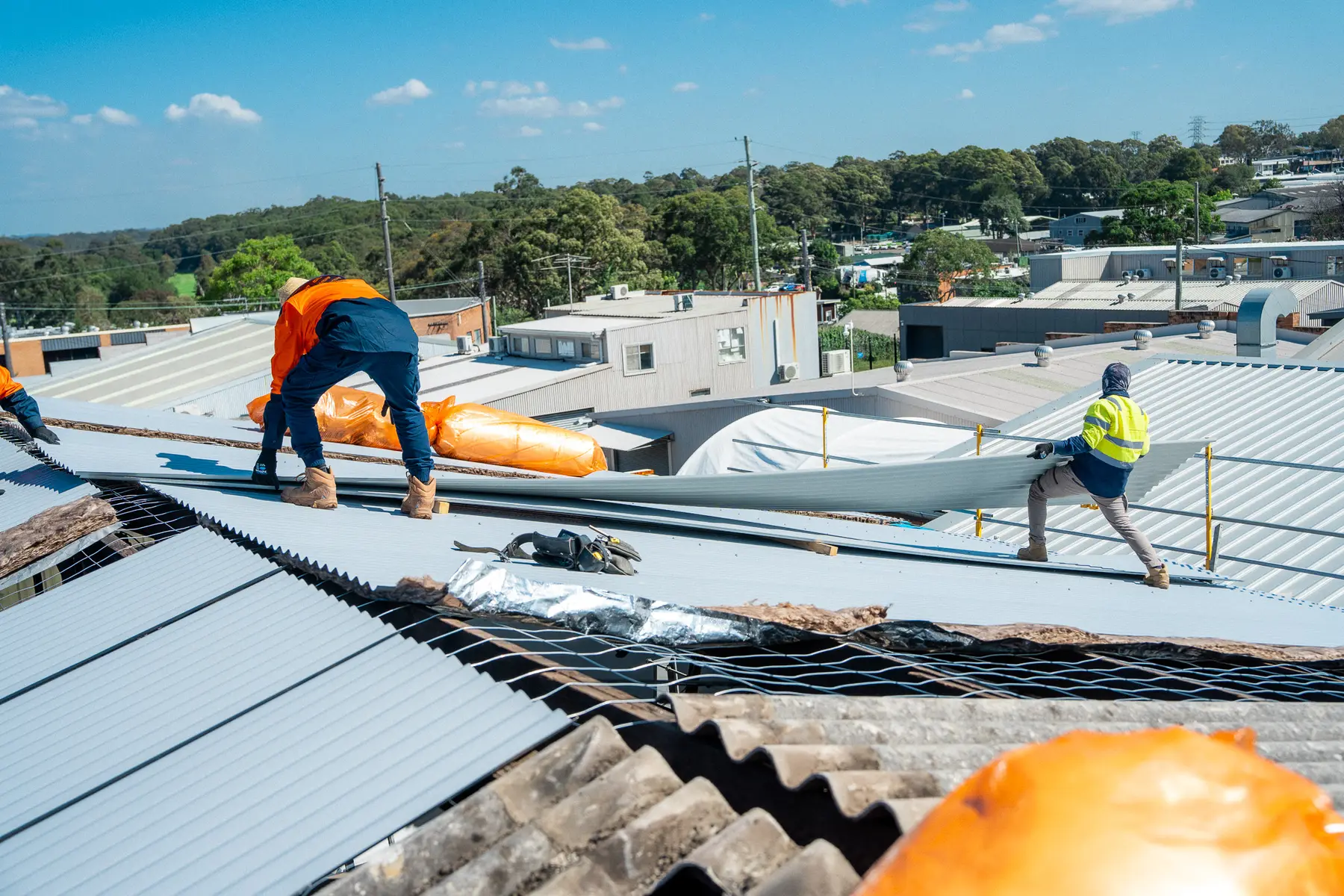 AD Roofing crew laying new sheets across a large industrial roof