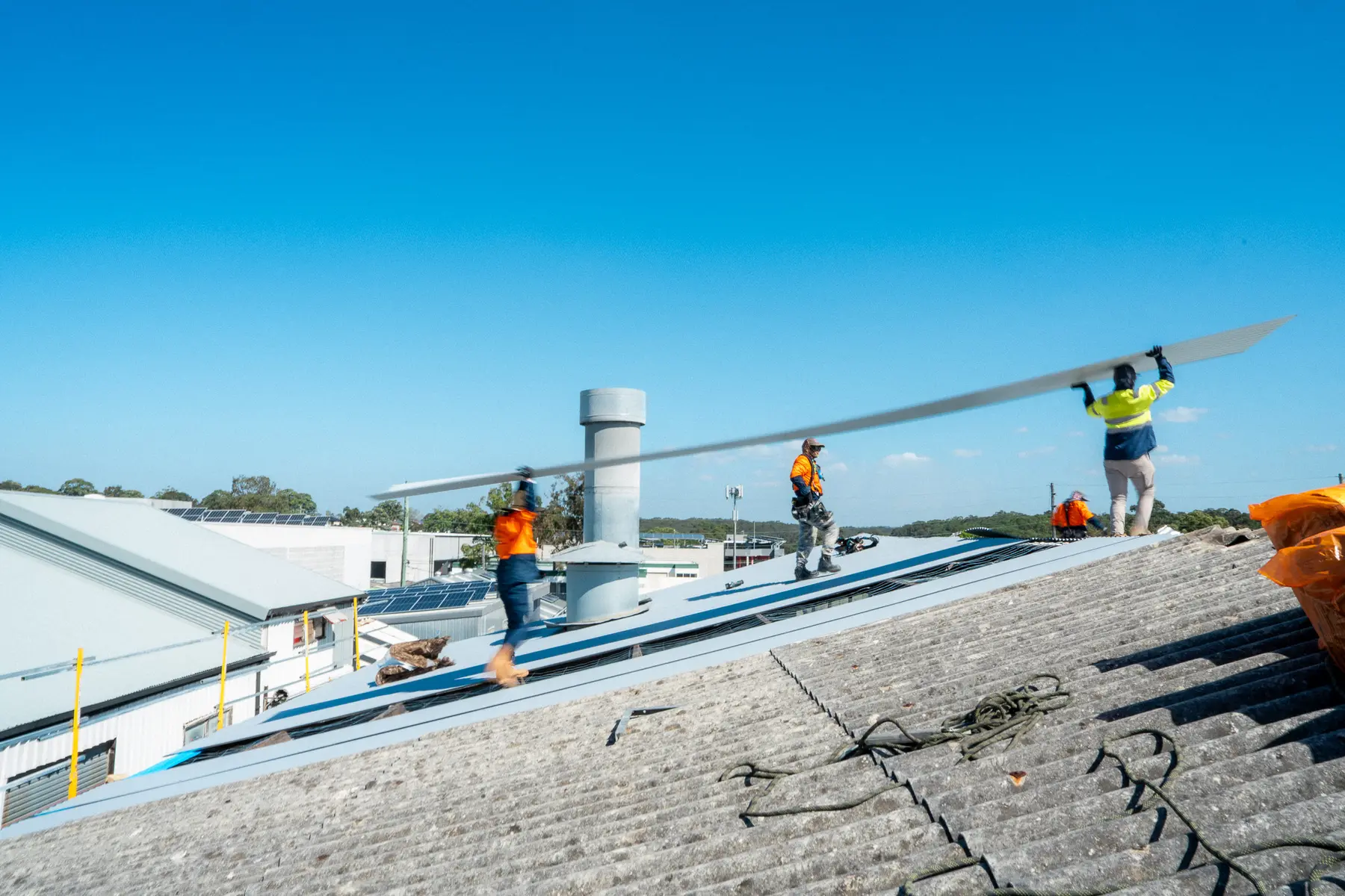 AD Roofing crew walking a new sheet over an old fibre-cement roof