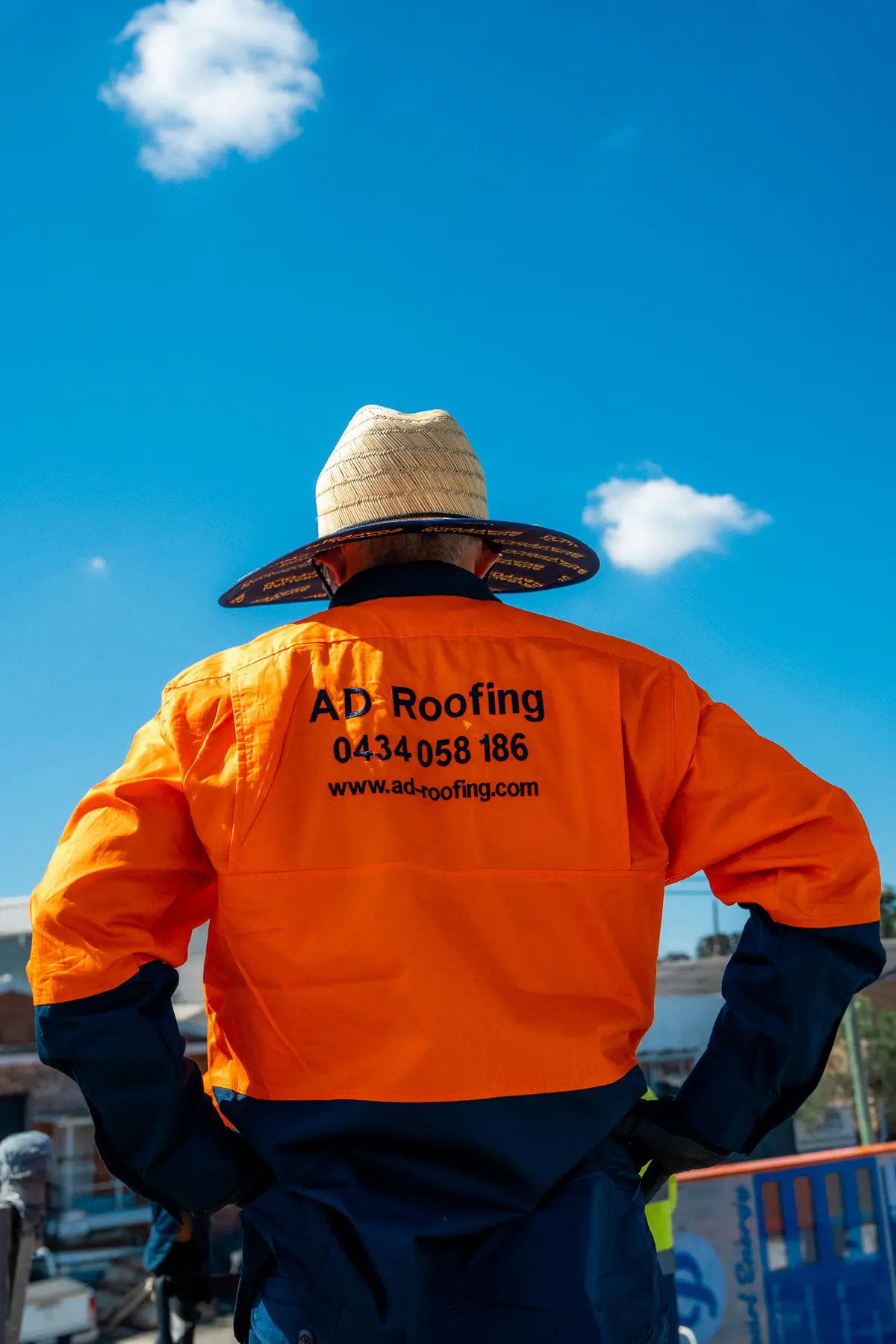 AD Roofing roofer in a branded orange work shirt overlooking the job