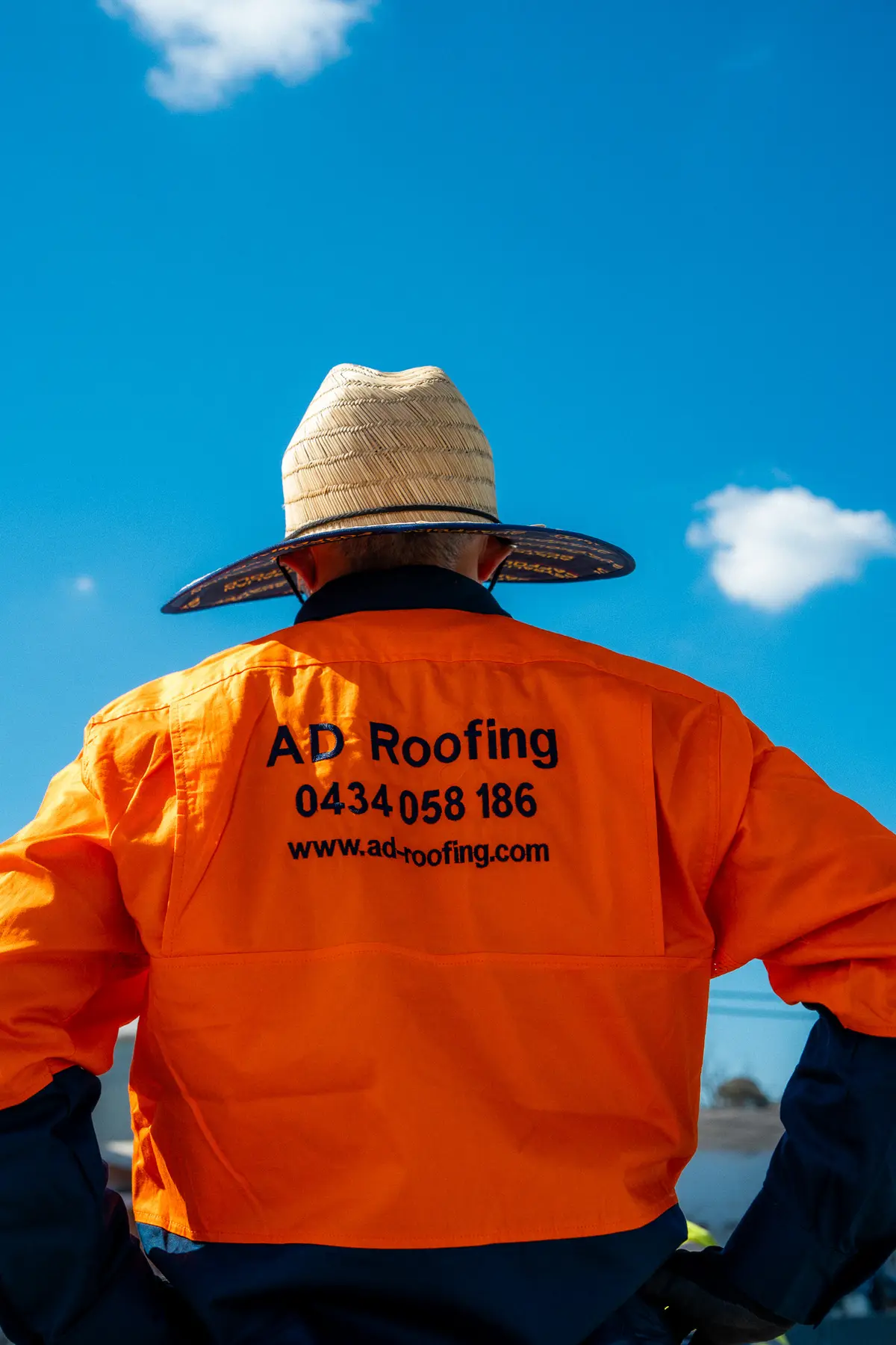AD Roofing roofer in a branded shirt and wide-brim hat on the roof