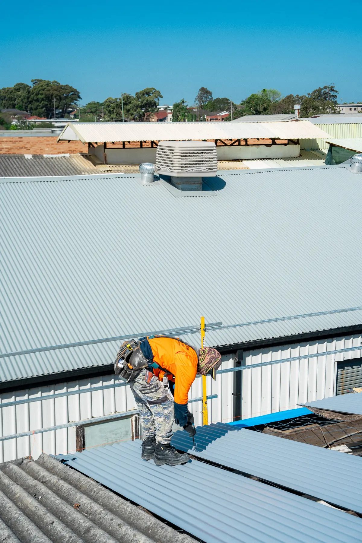 Roofer laying new sheets at the edge of the old fibre-cement roof