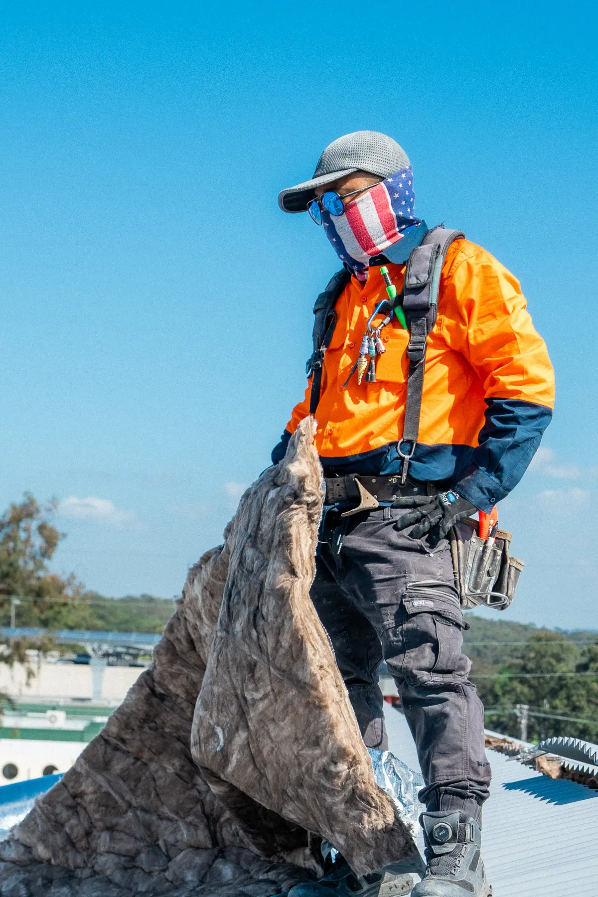 Roofer in a harness carrying away old roof insulation