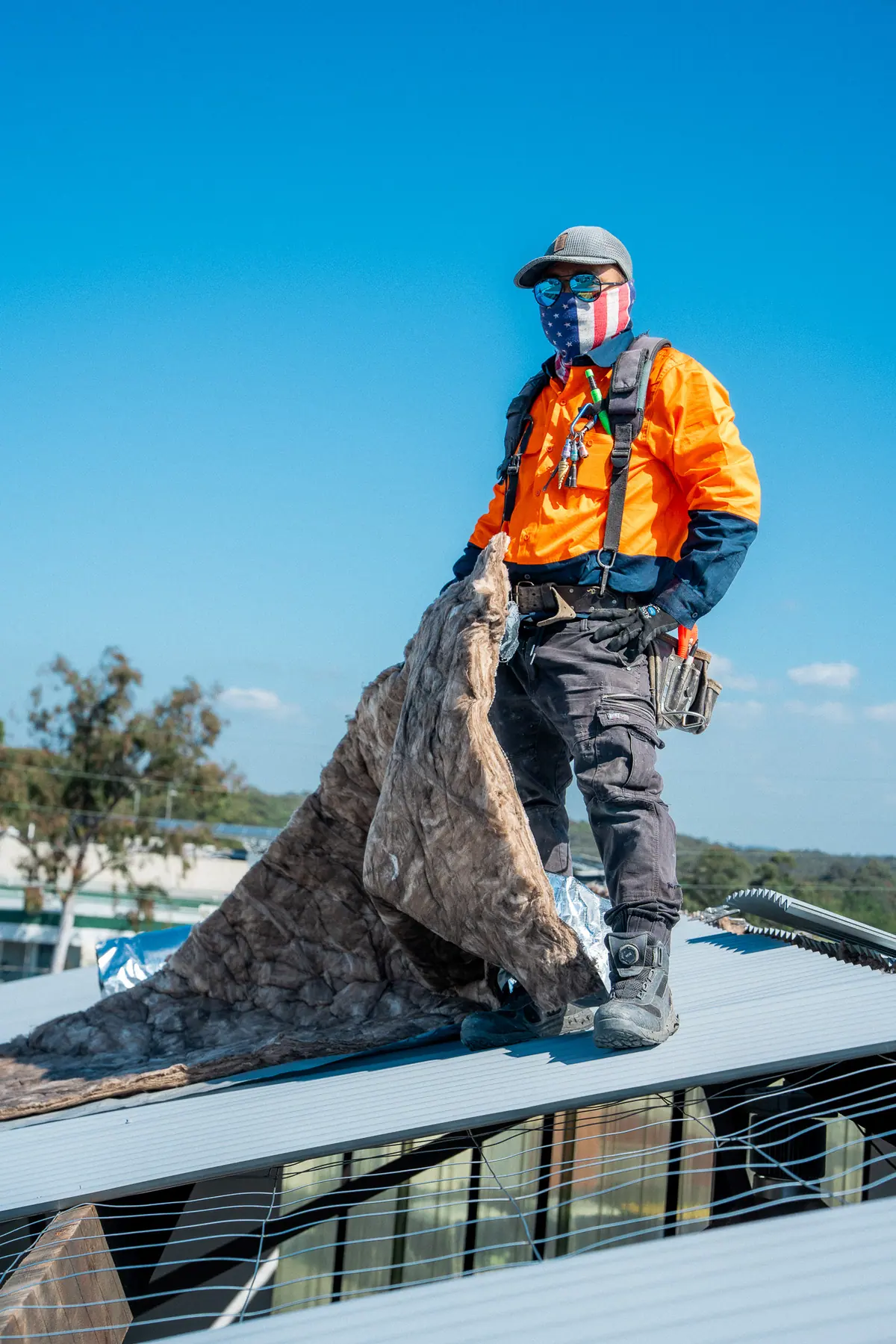 Roofer pulling up old insulation blanket from a stripped commercial roof