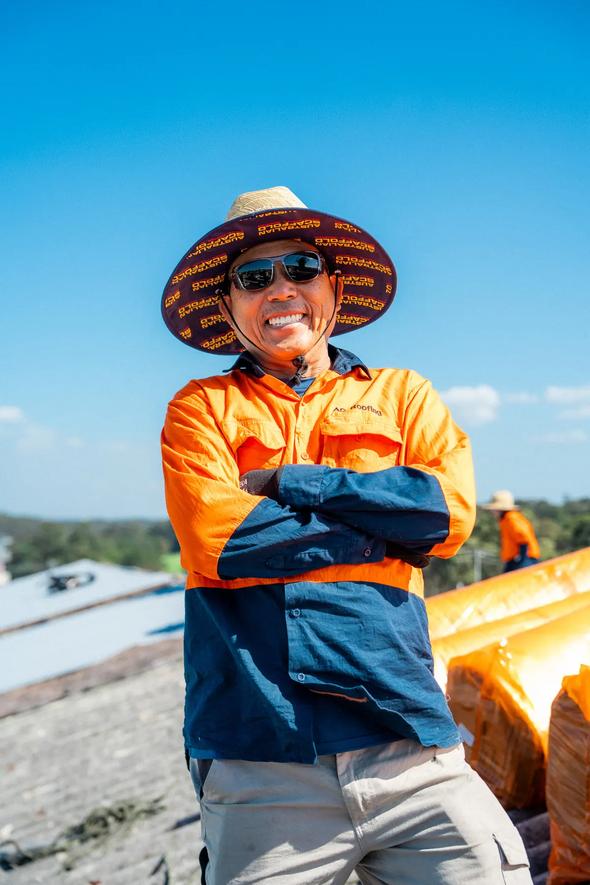 AD Roofing roofer in a wide-brim hat standing with arms crossed on the roof