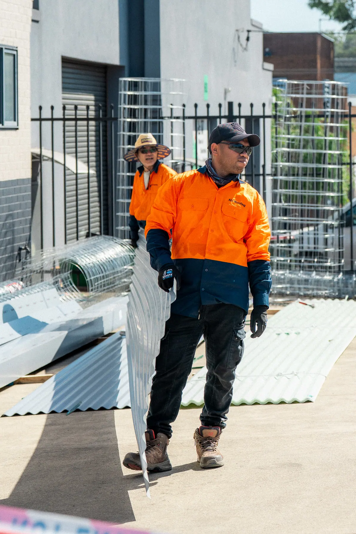 Roofer carrying a roof sheet through the site compound