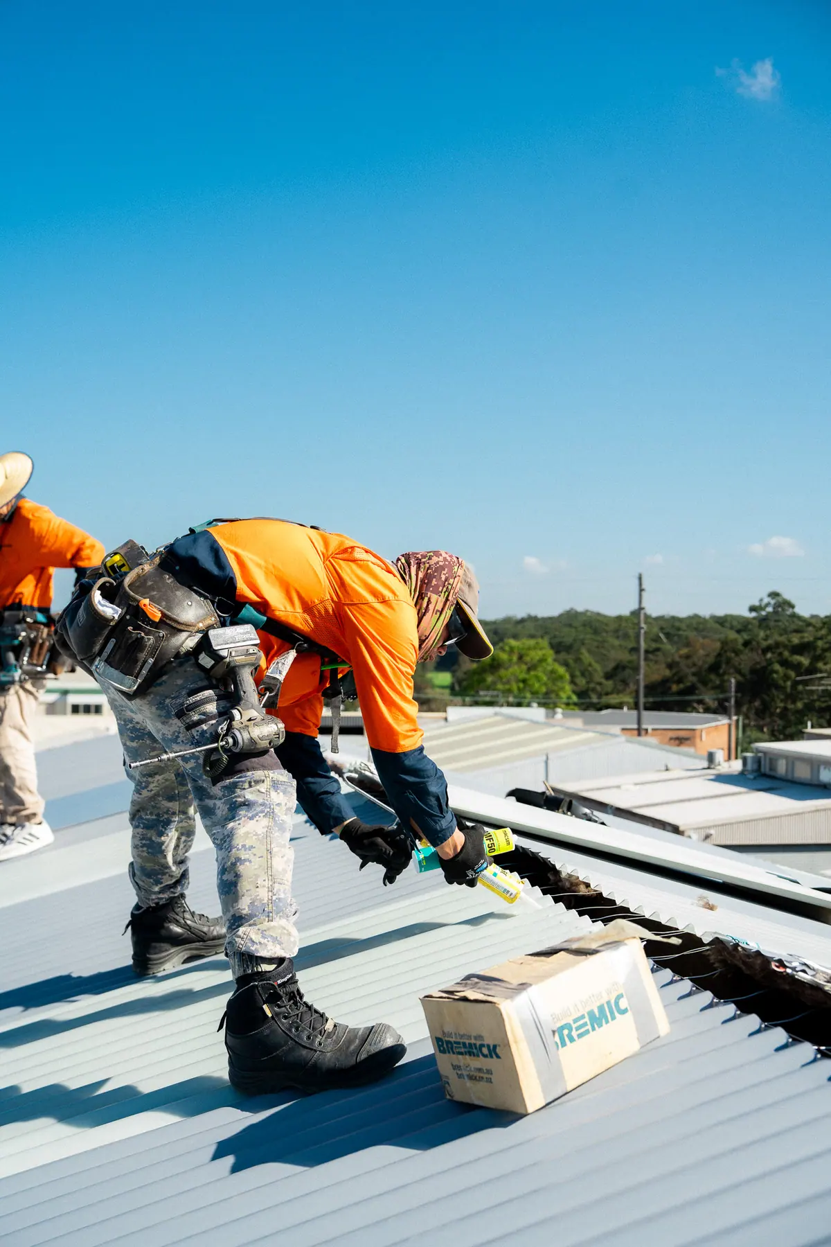 Roofer kneeling to fix down a new metal sheet