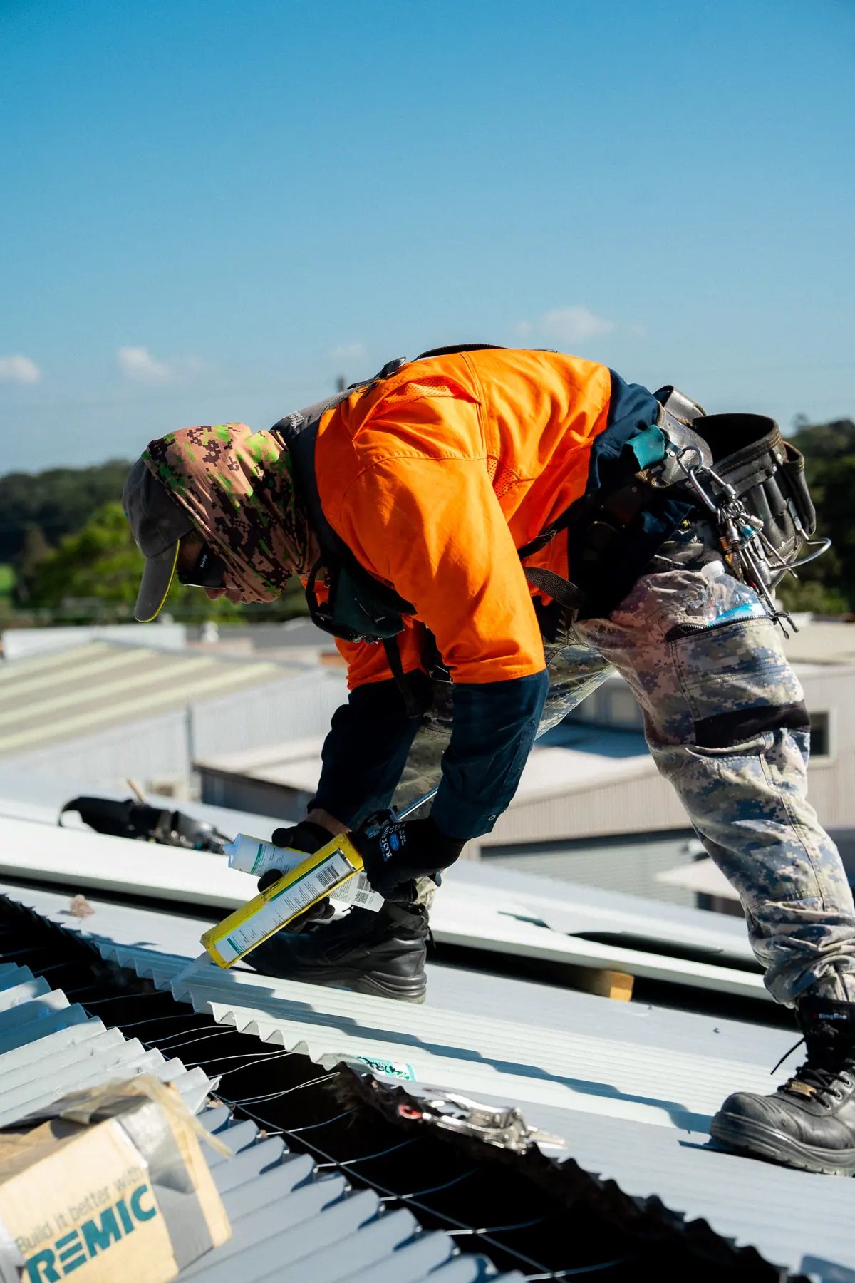 Roofer lining up a new sheet with boxes of roofing screws close at hand