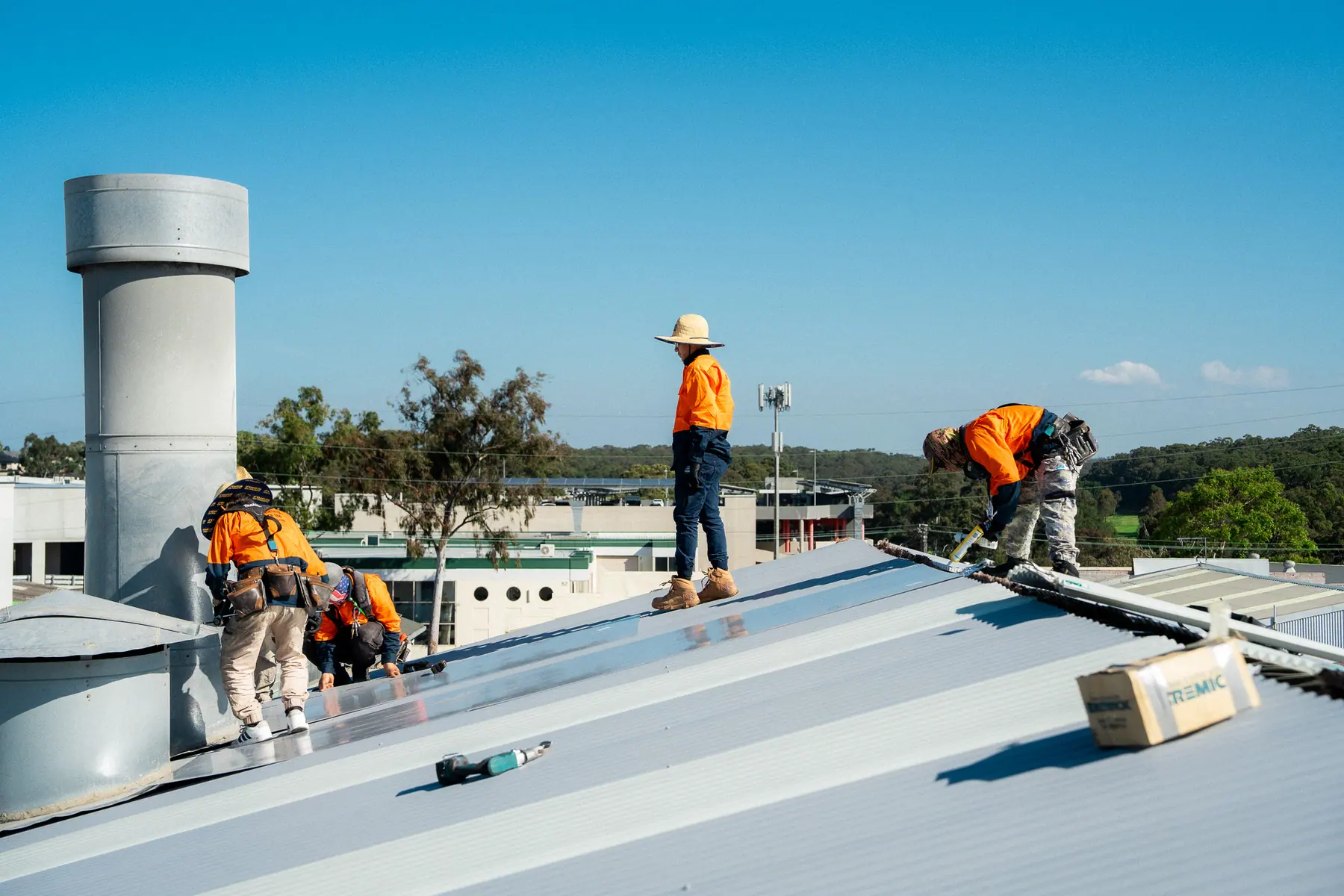 Crew fixing new metal roof sheets around a roof ventilator