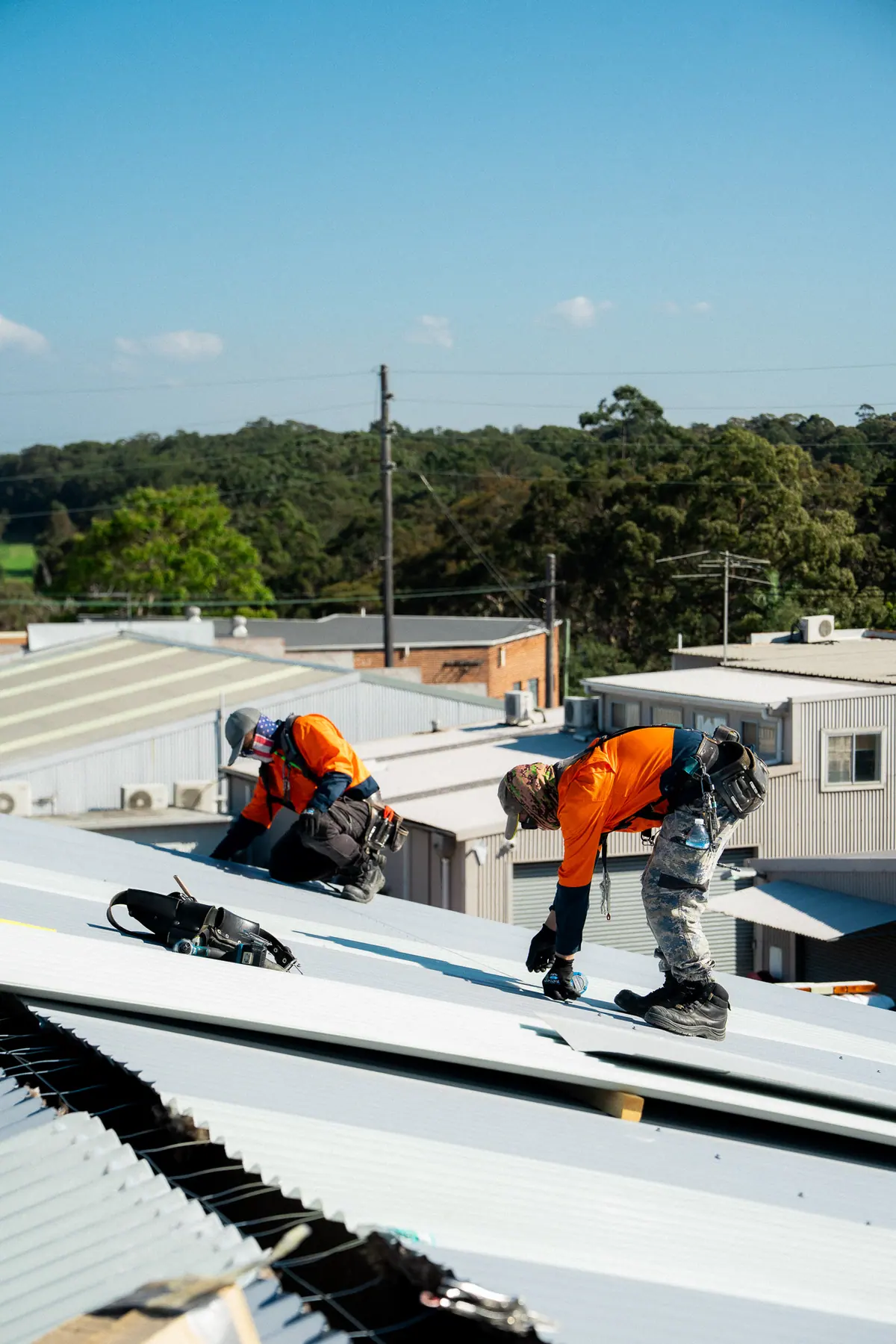 Two roofers fixing the ends of new roof sheets