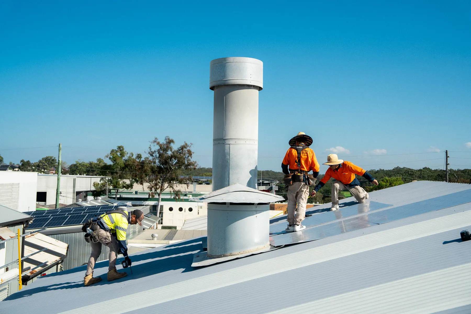 Roofers working around a roof ventilator on the new metal roof