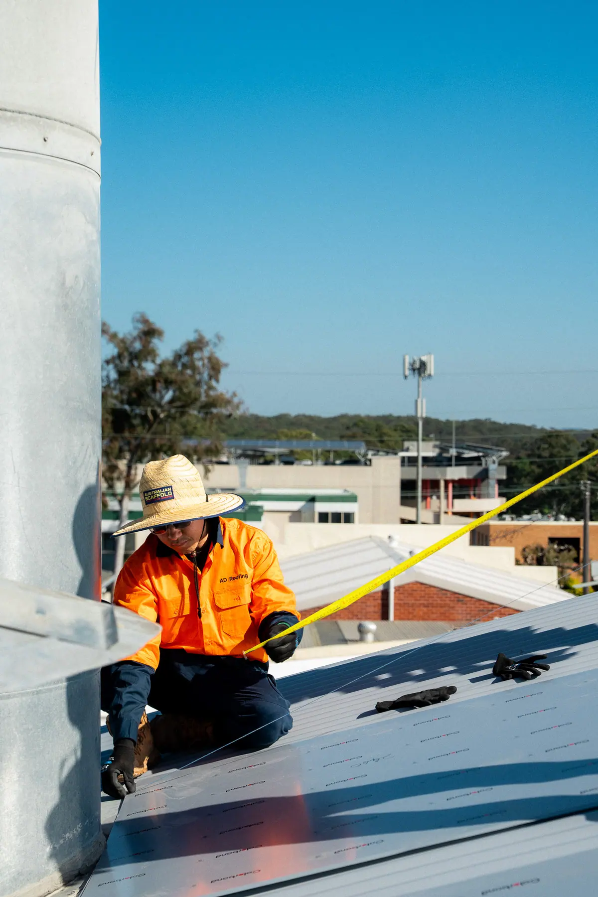 Roofer measuring along the new sheeting beside the ventilator
