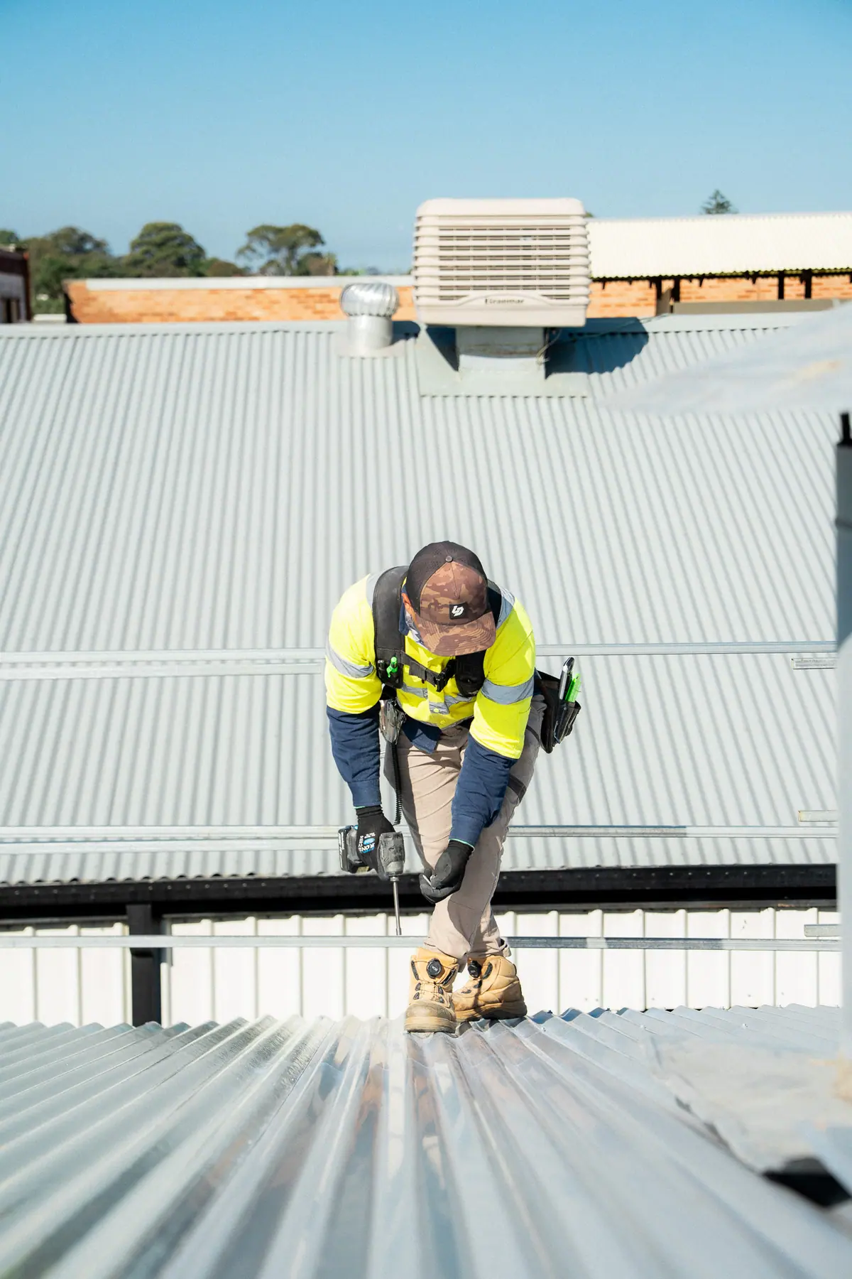 Roofer drilling fixings into the new corrugated roof
