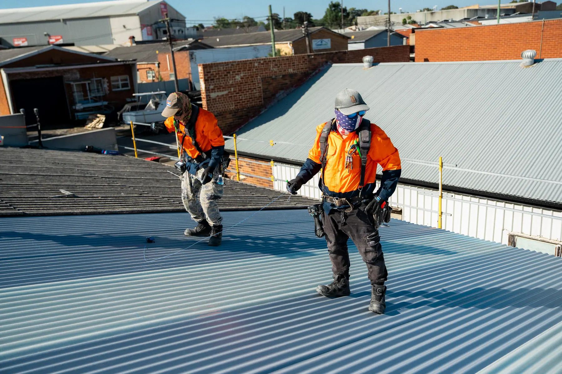 Roofers walking the roof between the old roof and the new sheeting
