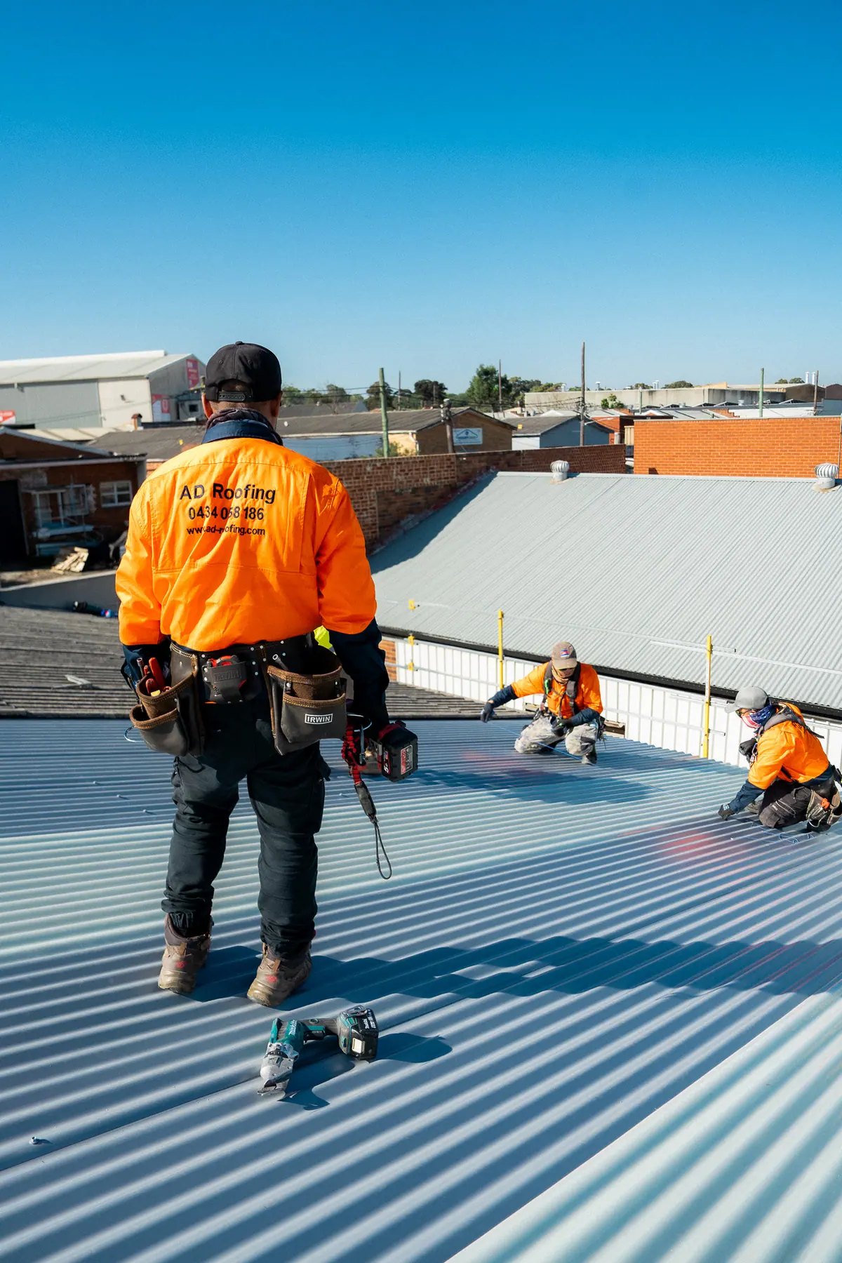 Roofer in an AD Roofing shirt walking across the new metal roof