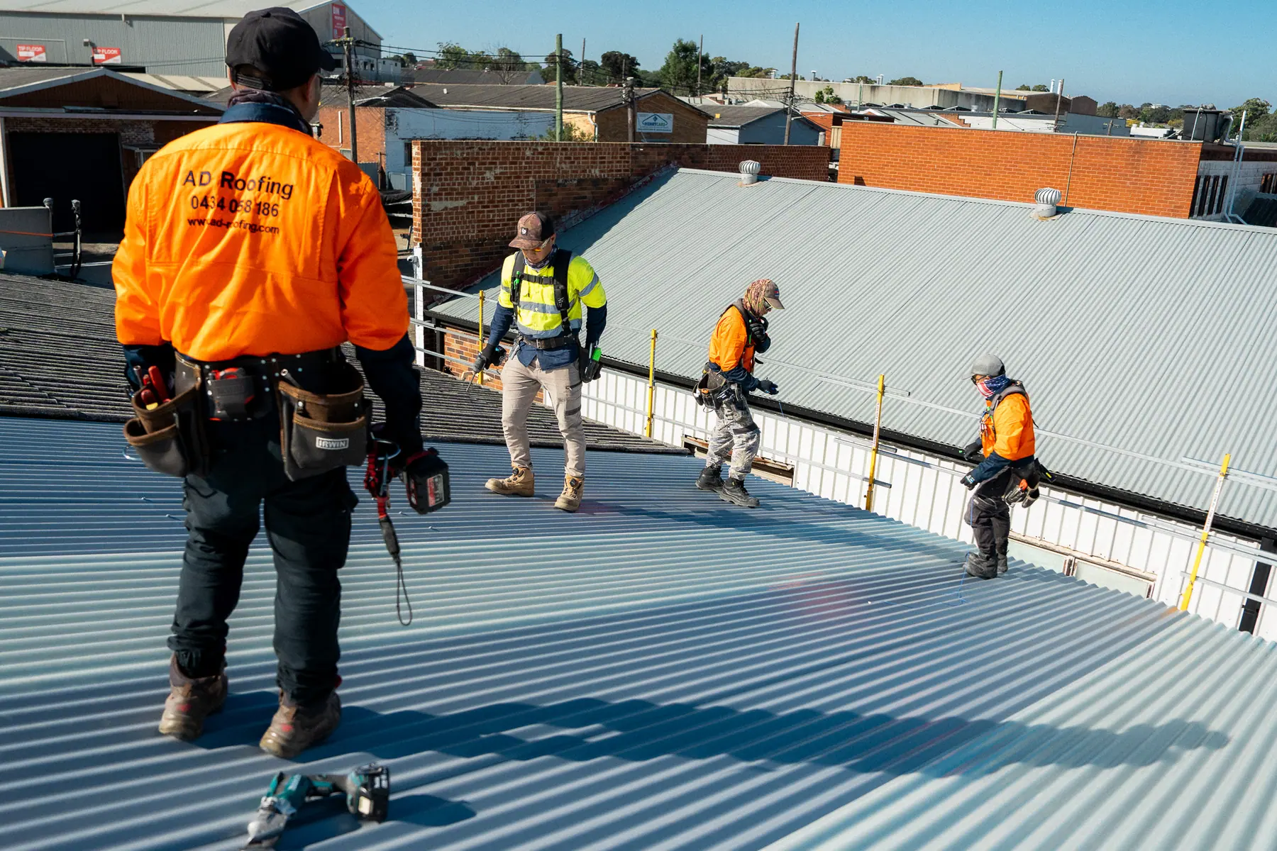 AD Roofing roofer watching the crew lay new sheets across the roof