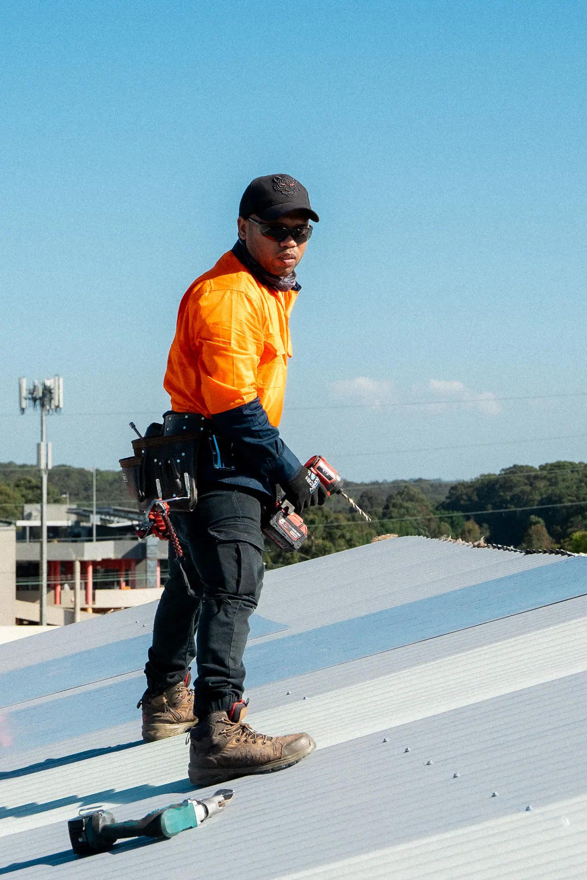 Roofer standing on the new sheets with a drill in hand