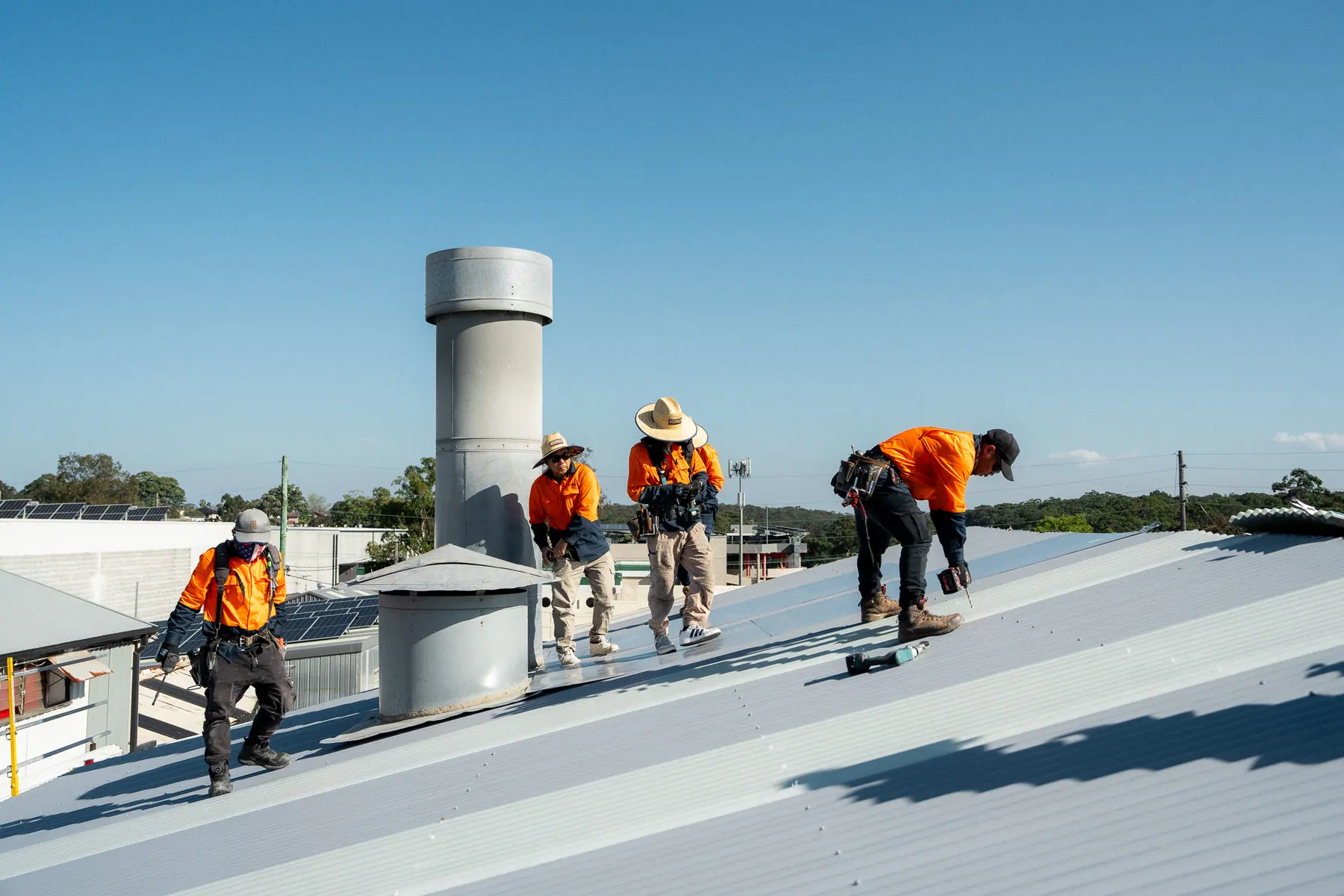 Roofers fixing new sheets near the ventilator on a large commercial roof