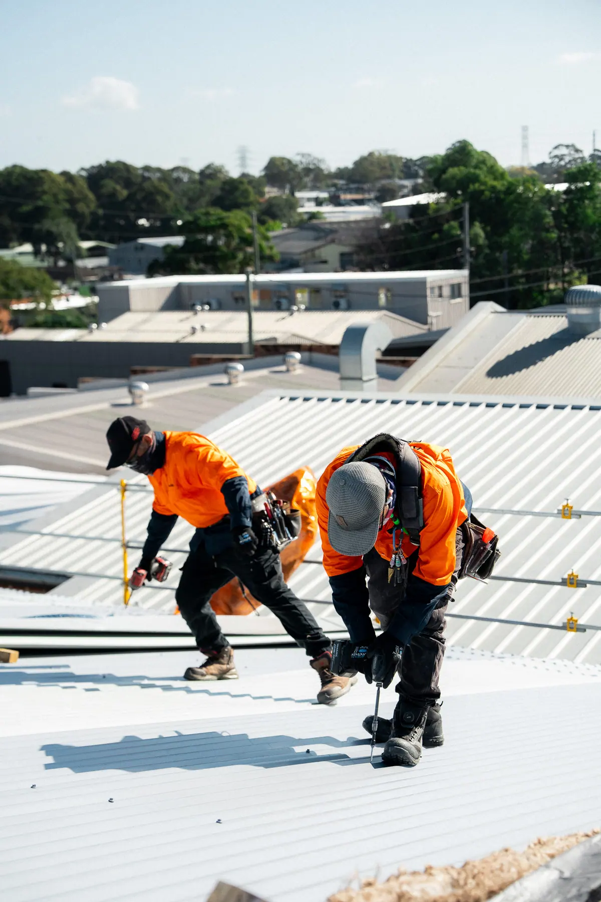 Two roofers laying a new sheet along the edge protection