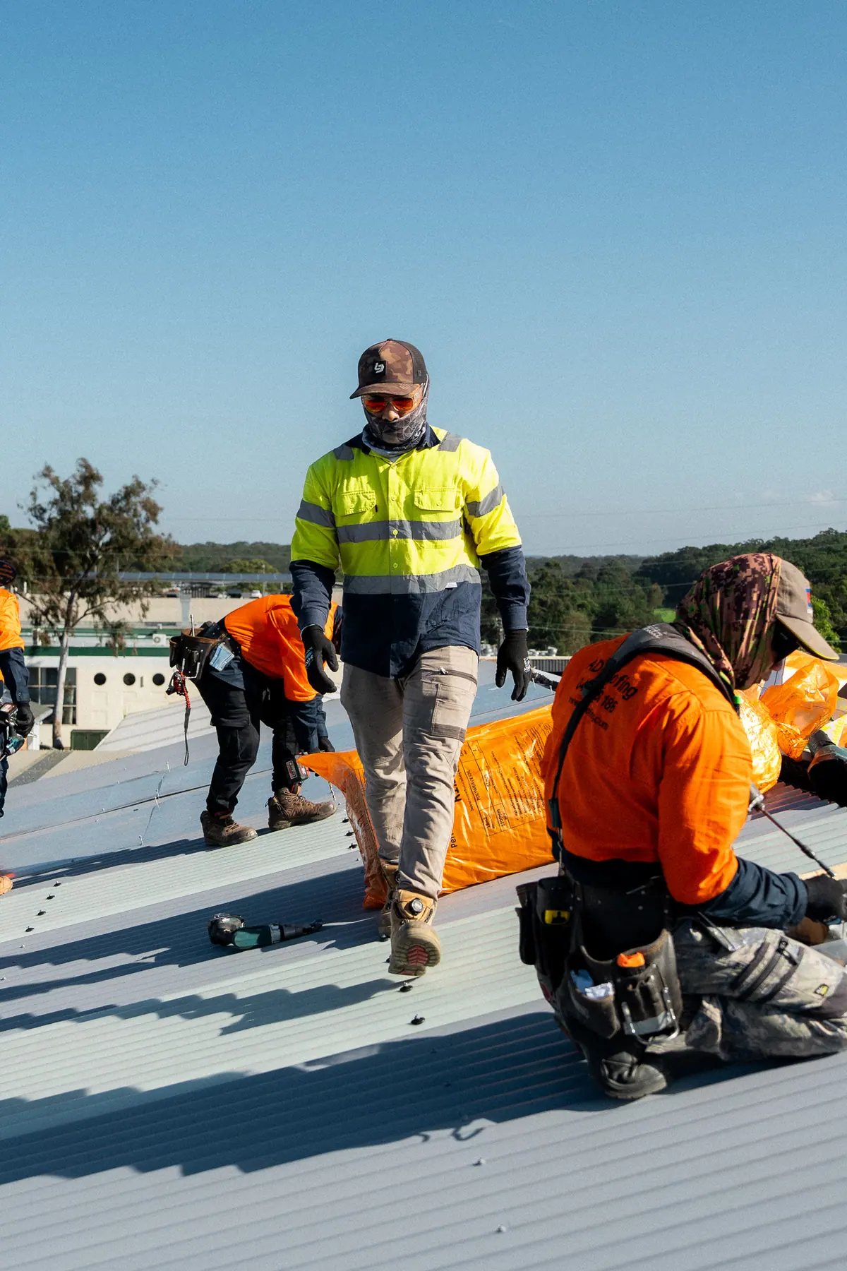 Crew laying insulation blanket ahead of the new roof sheets
