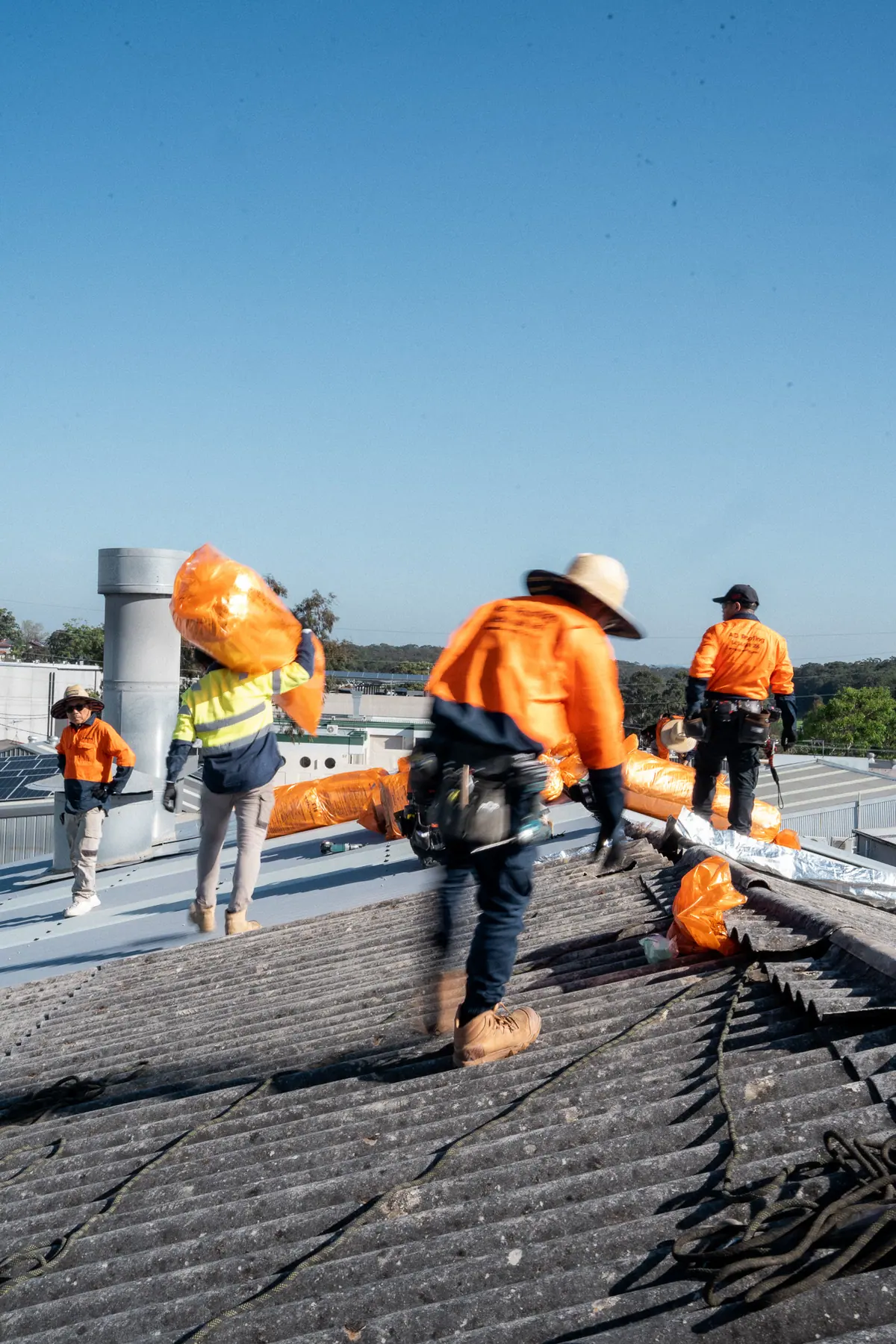 Roofer on the old fibre-cement roof with insulation rolls ready to go down