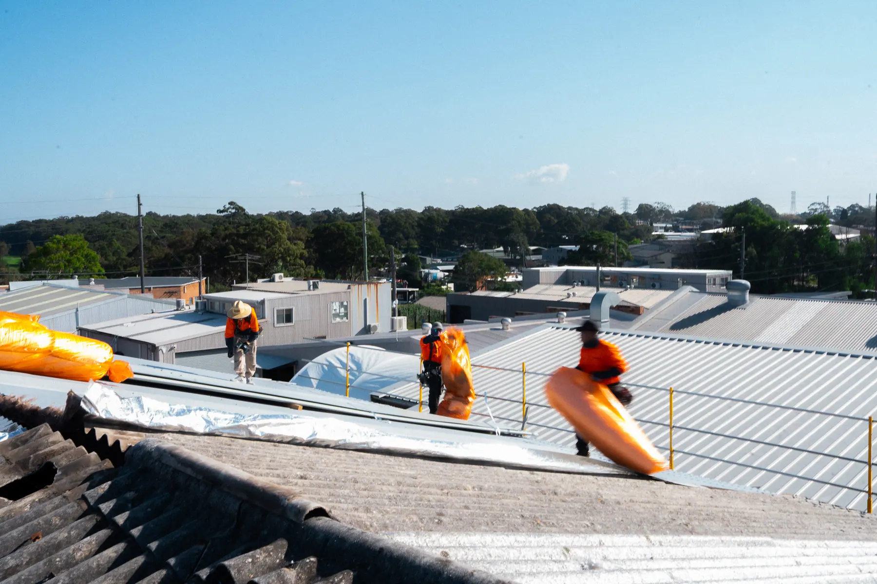 Insulation rolls staged on the roof as the old fibre-cement sheets come off